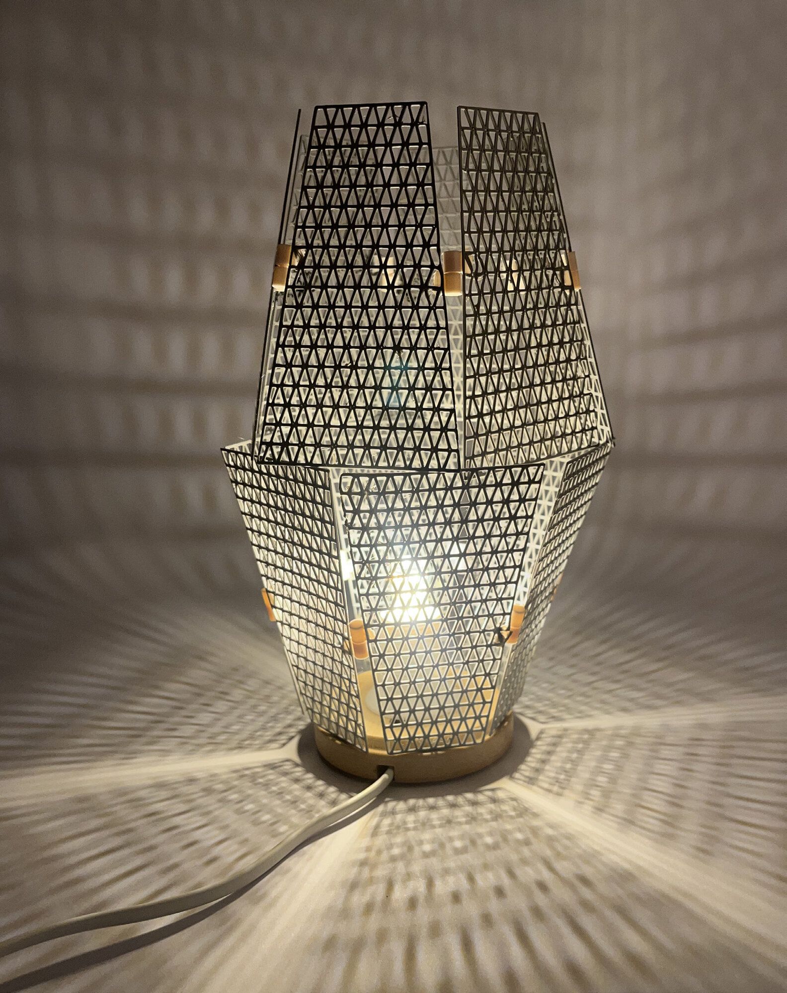 Lampe Trikitlight allumée projetant un motif triangulaire au mur.